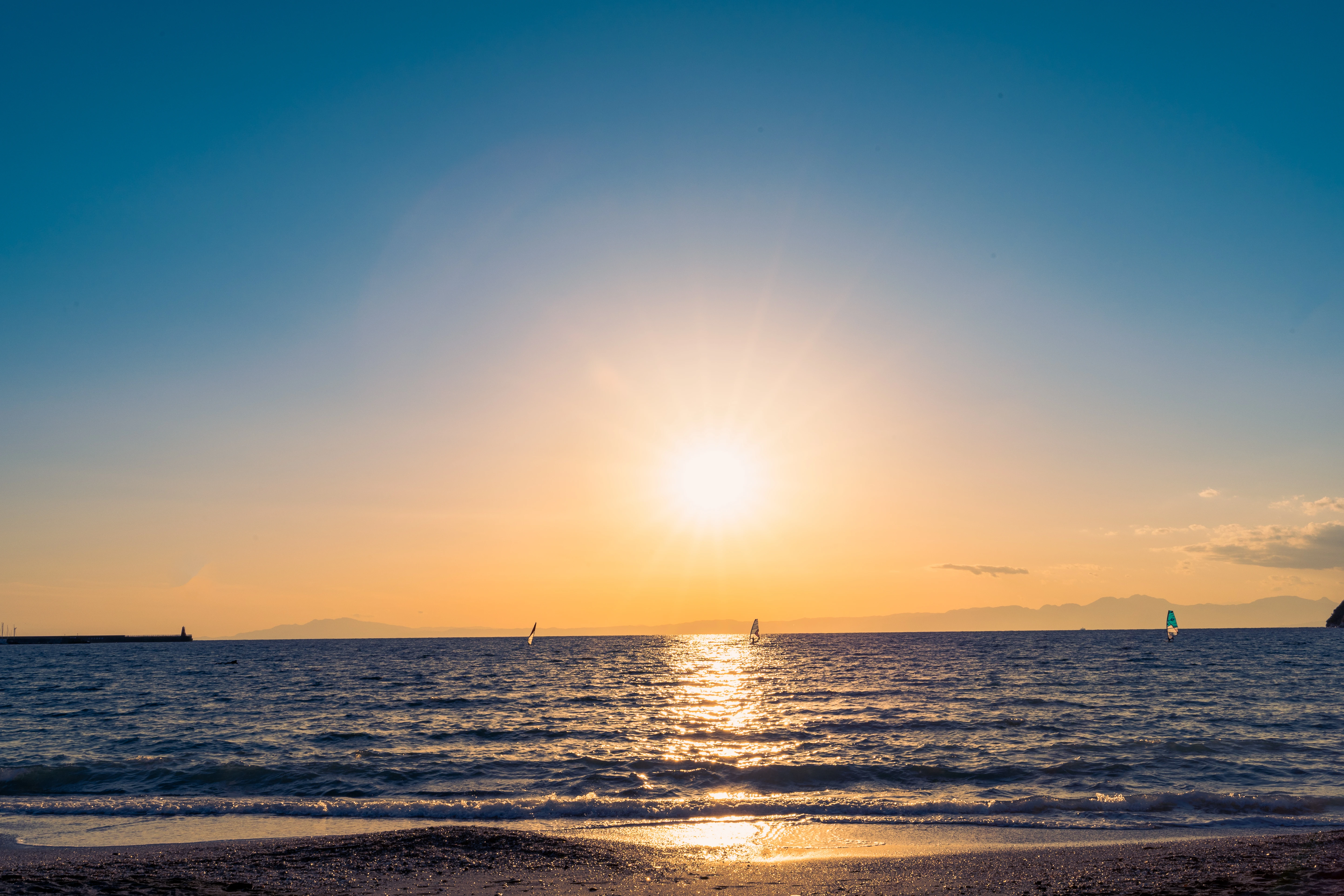 Golden Sunset Over Tranquil Waters with Windsurfers