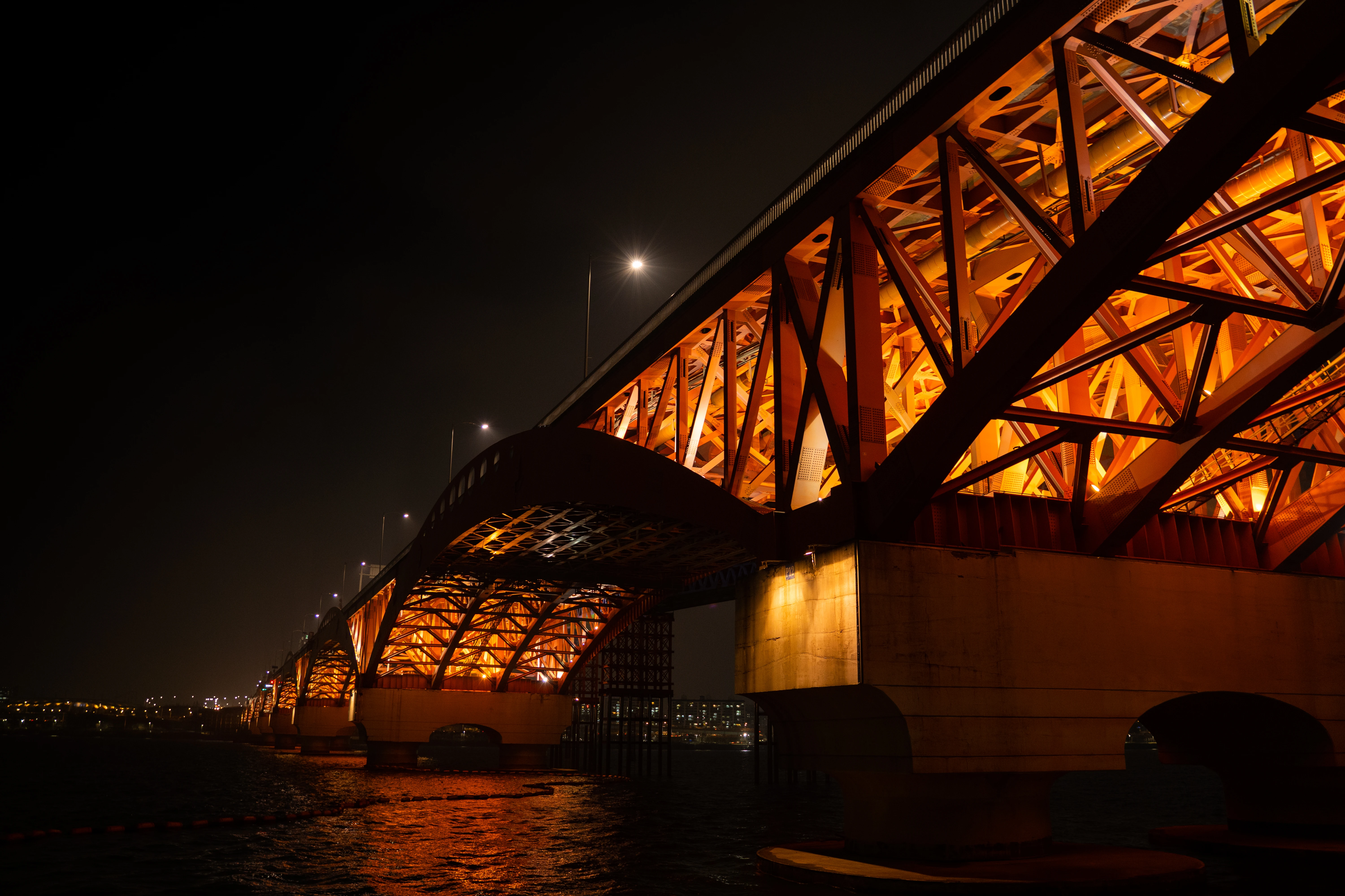 Illuminated Bridge Structure at Night Over a Reflective River
