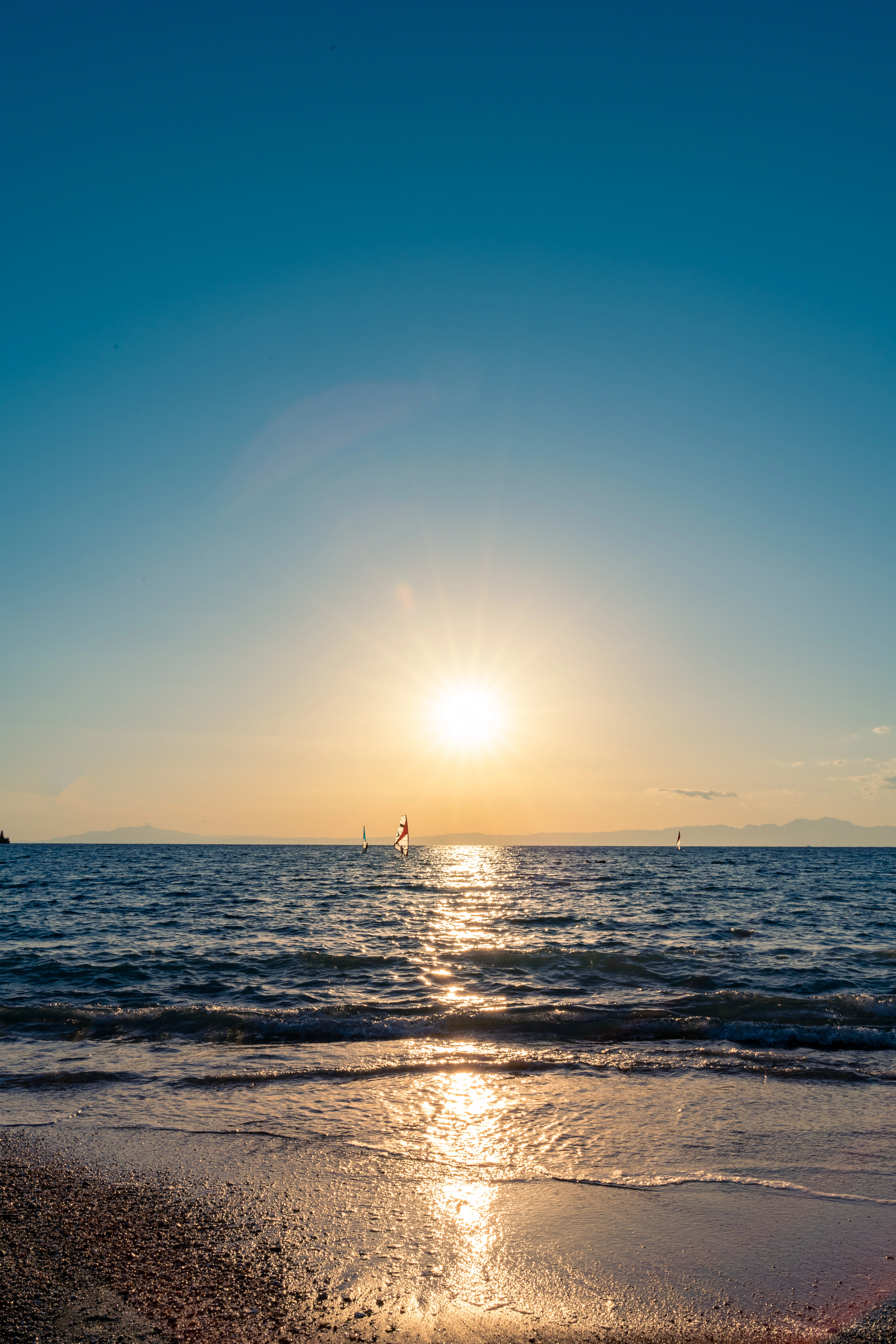 Sailboats gliding under the golden sunset over tranquil waters