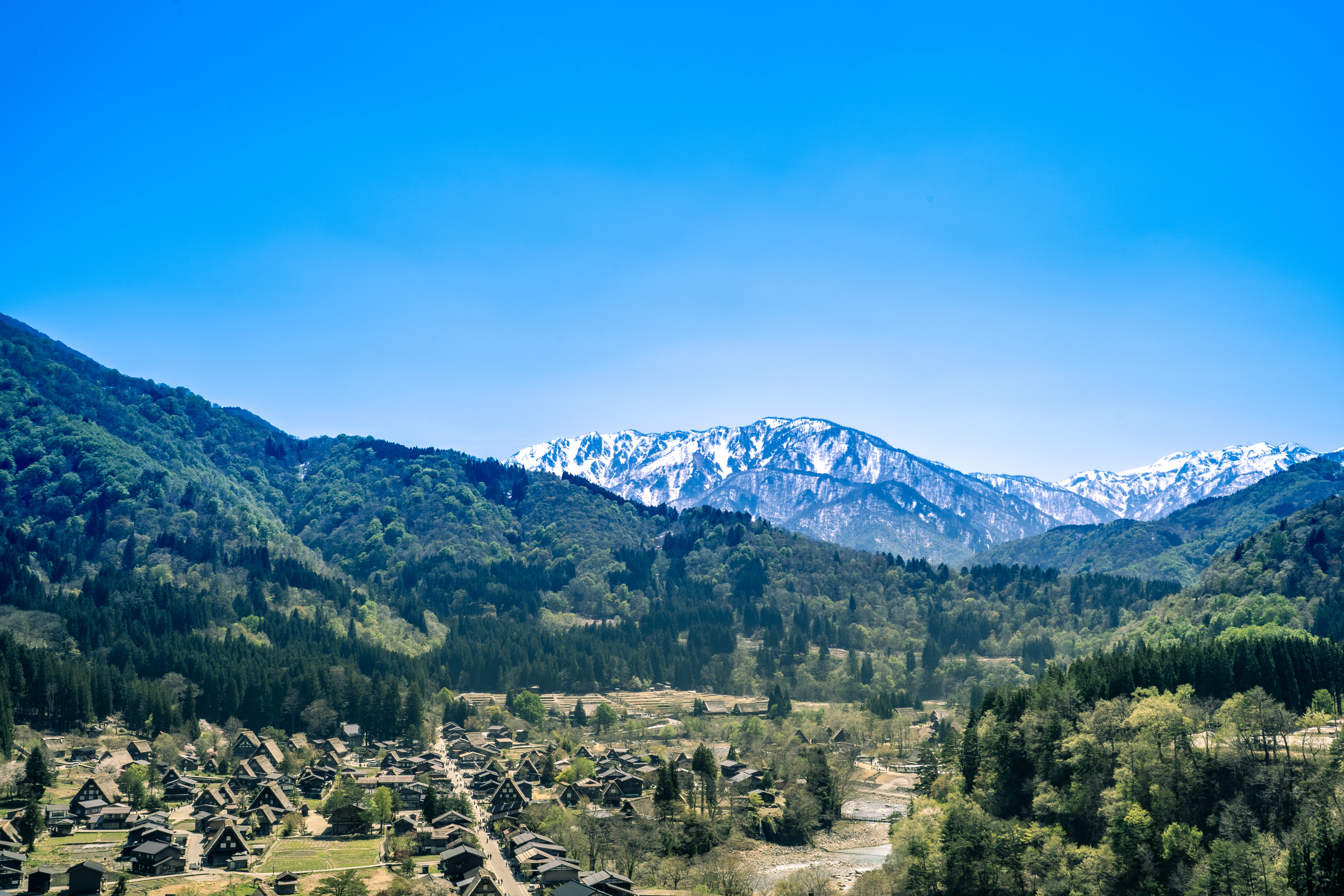 Tranquil Village Nestled in Verdant Spring Mountains With Snowy Peaks