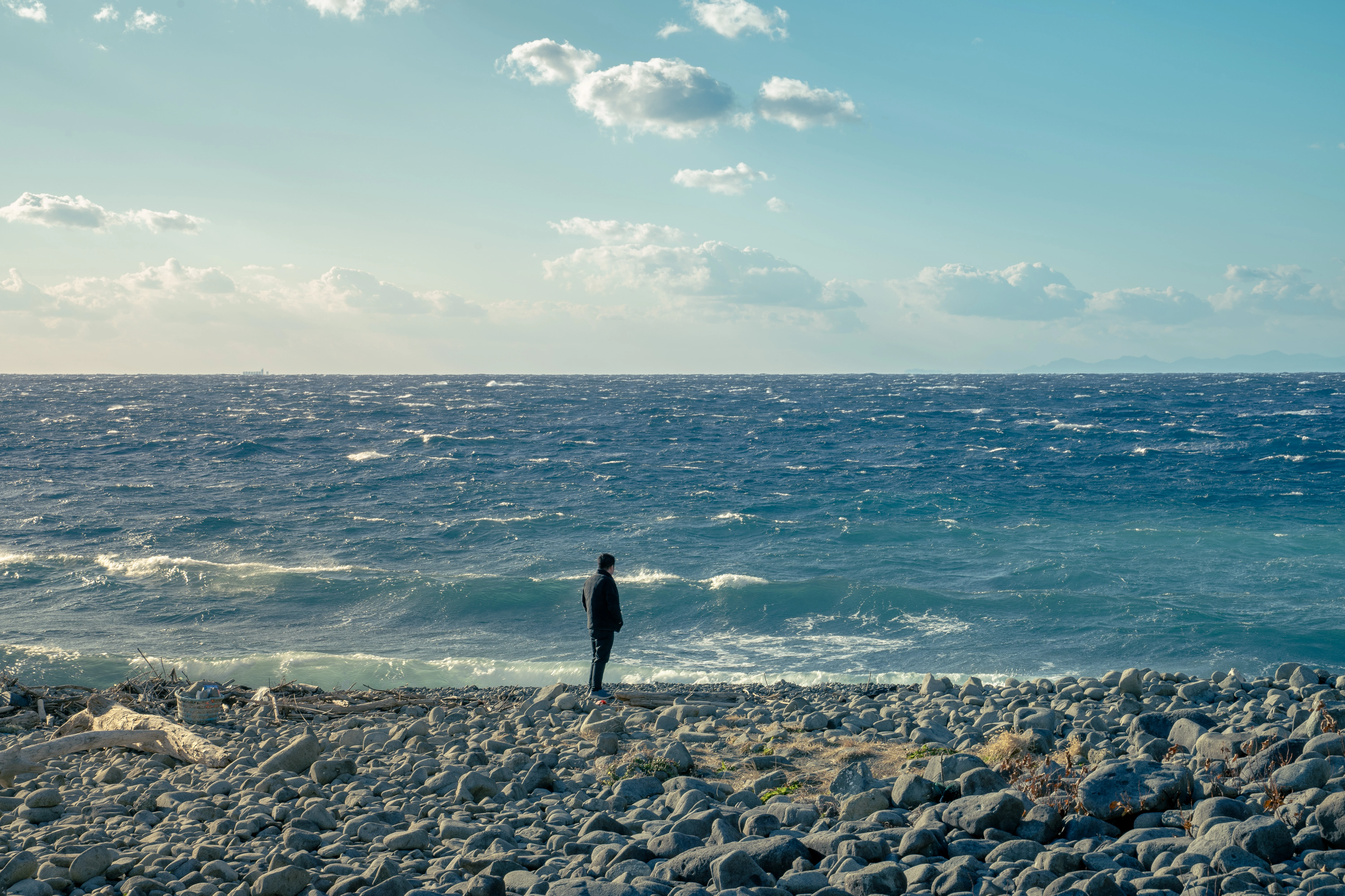 Man Standing on a Rocky Beach Overlooking The Ocean