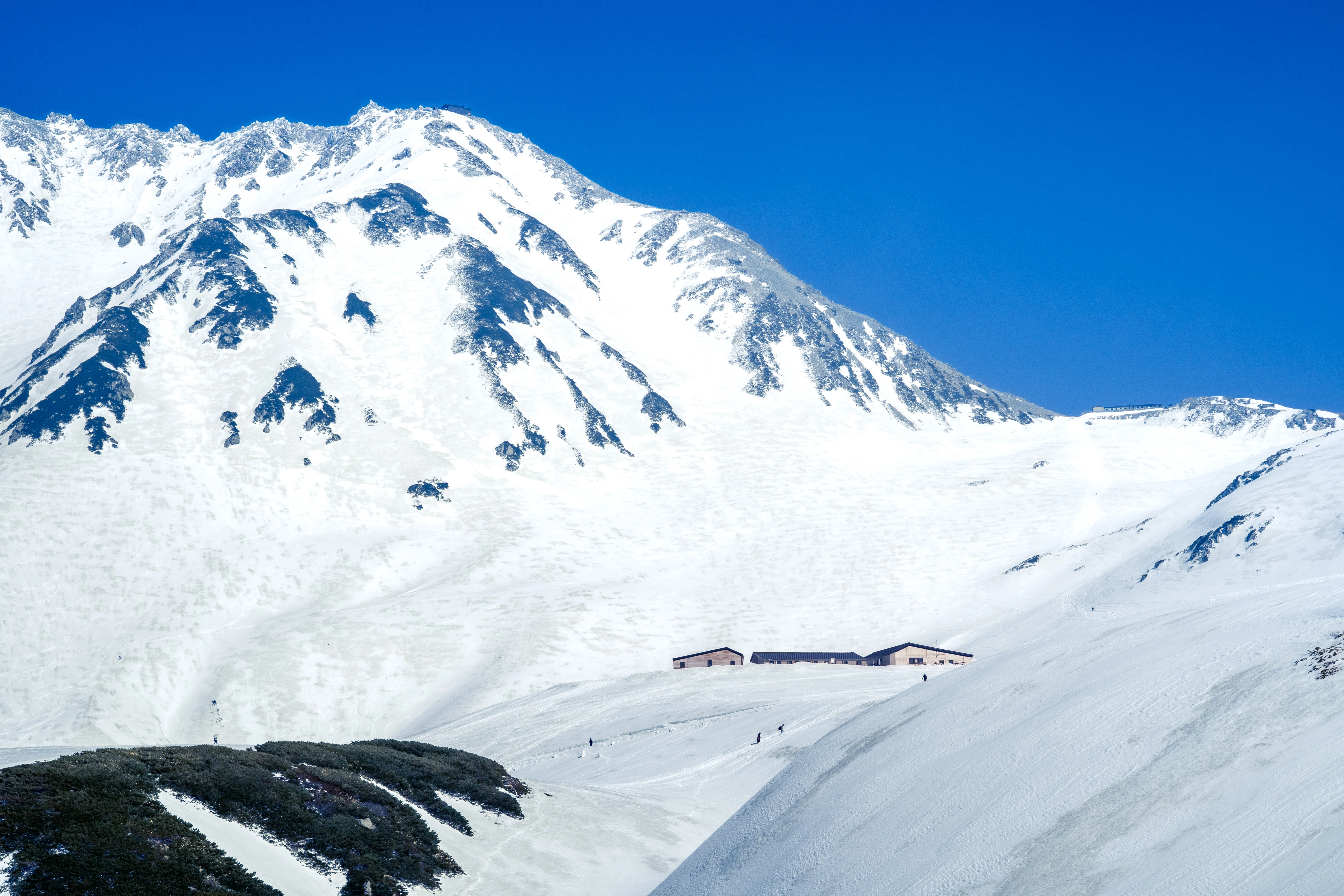 Tranquil Alpine Lodge Nestled in Snowy Peaks Under a Clear Blue Sky