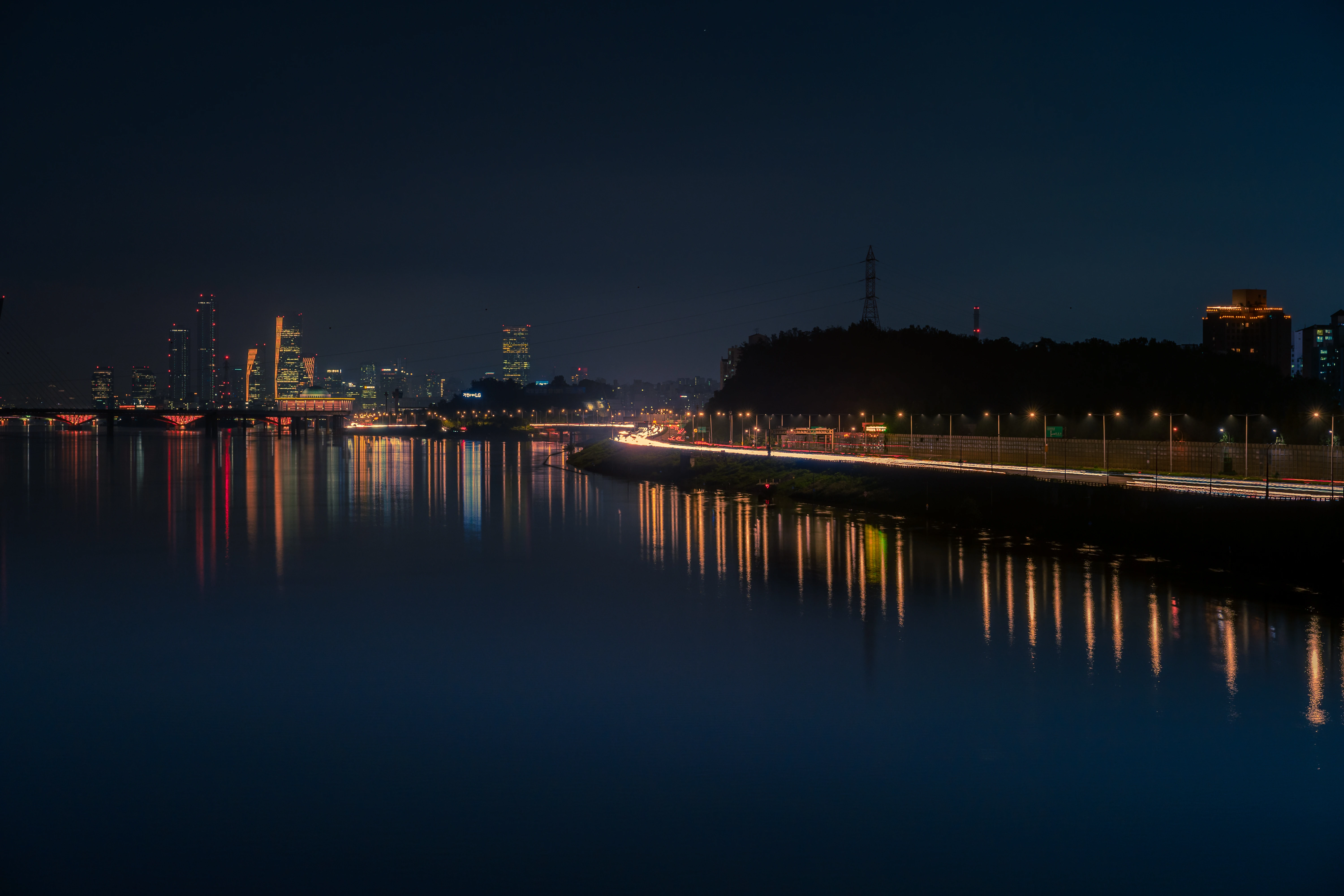 Reflections of Urban Nightlife Along the Quiet Riverside