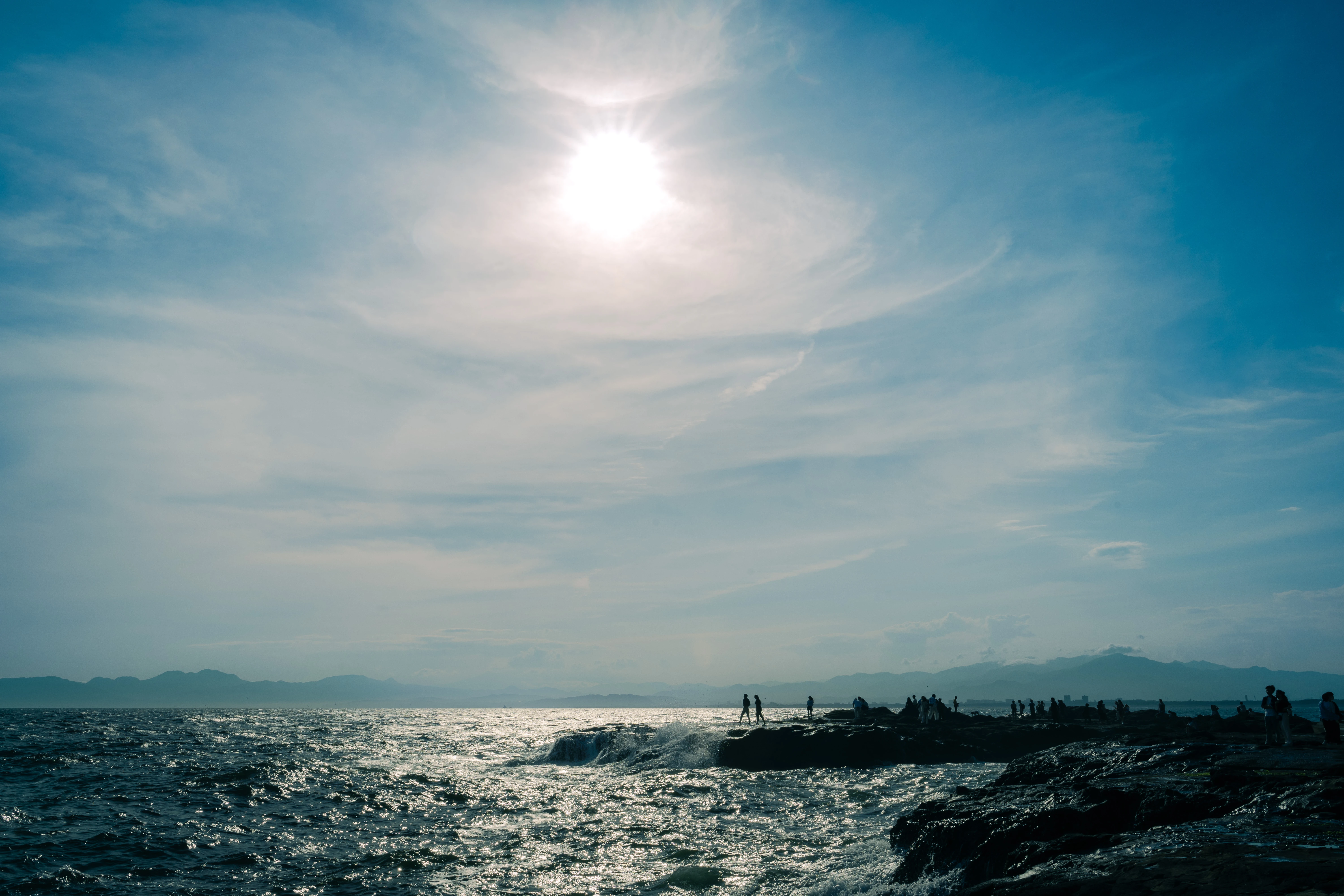 Shimmering Sea and Silhouetted Figures under a Sunlit Sky