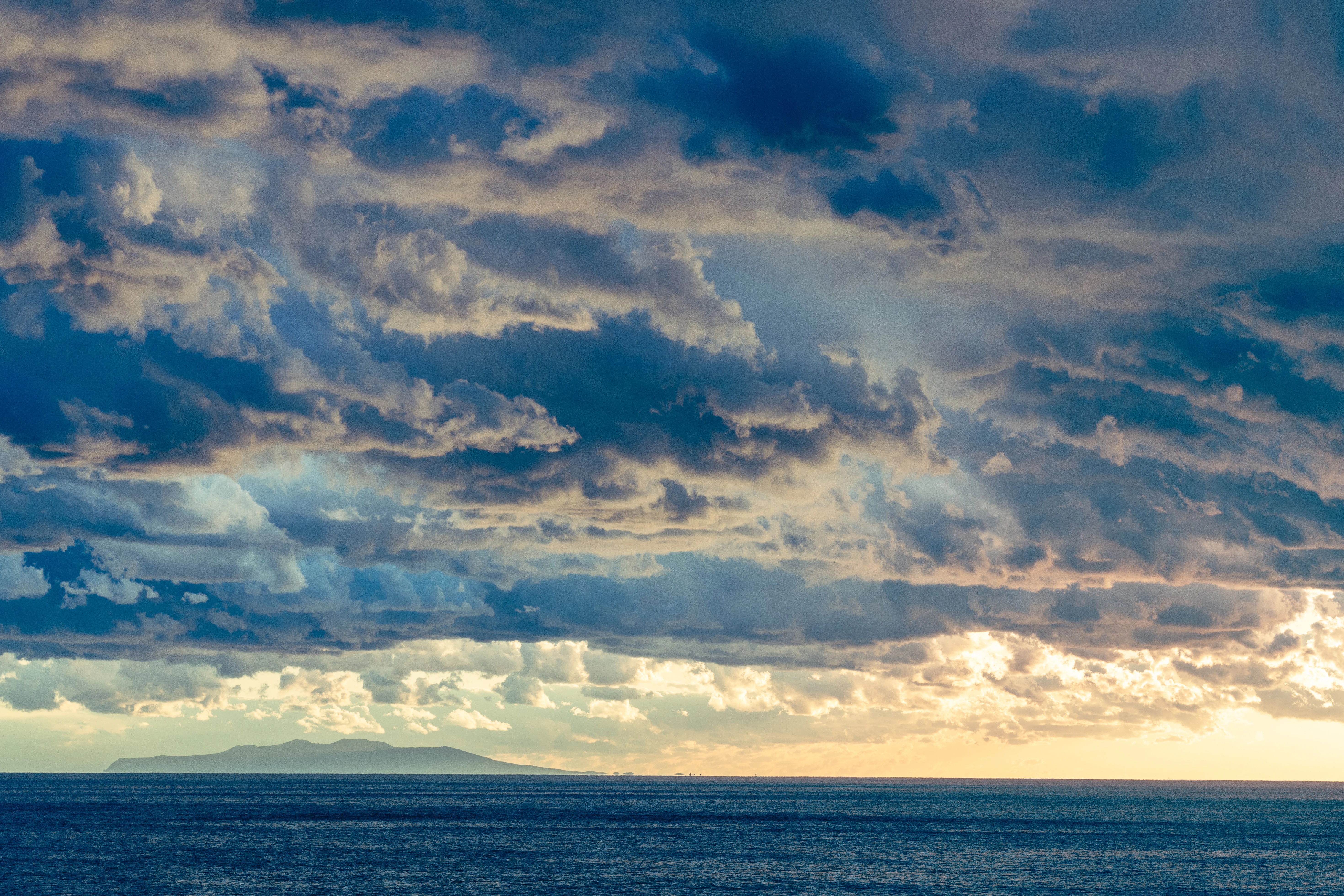 Dramatic Sky Over Distant Island and Ocean Horizon