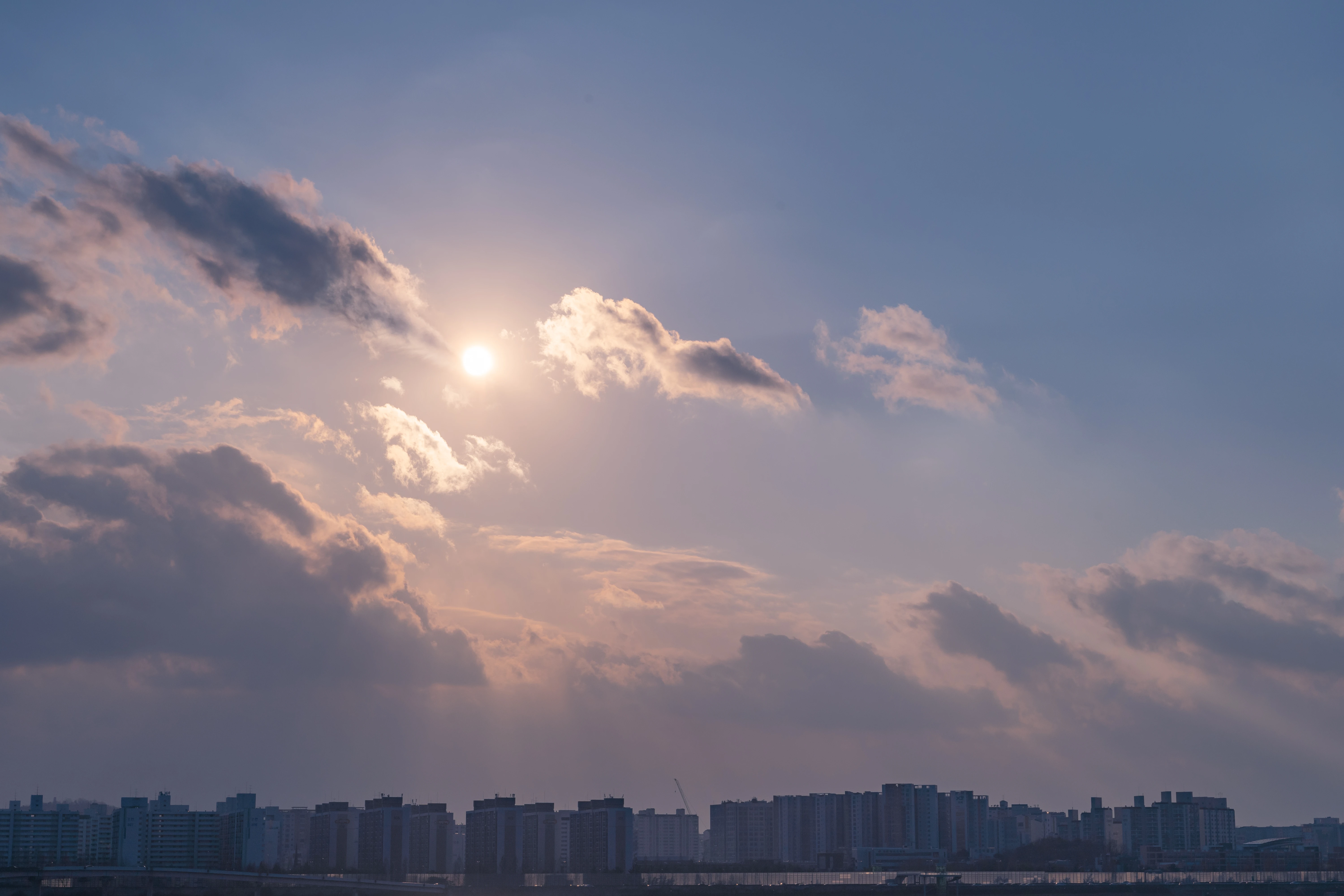 Sunlit Clouds Over City Skylines - A Tranquil Harmony