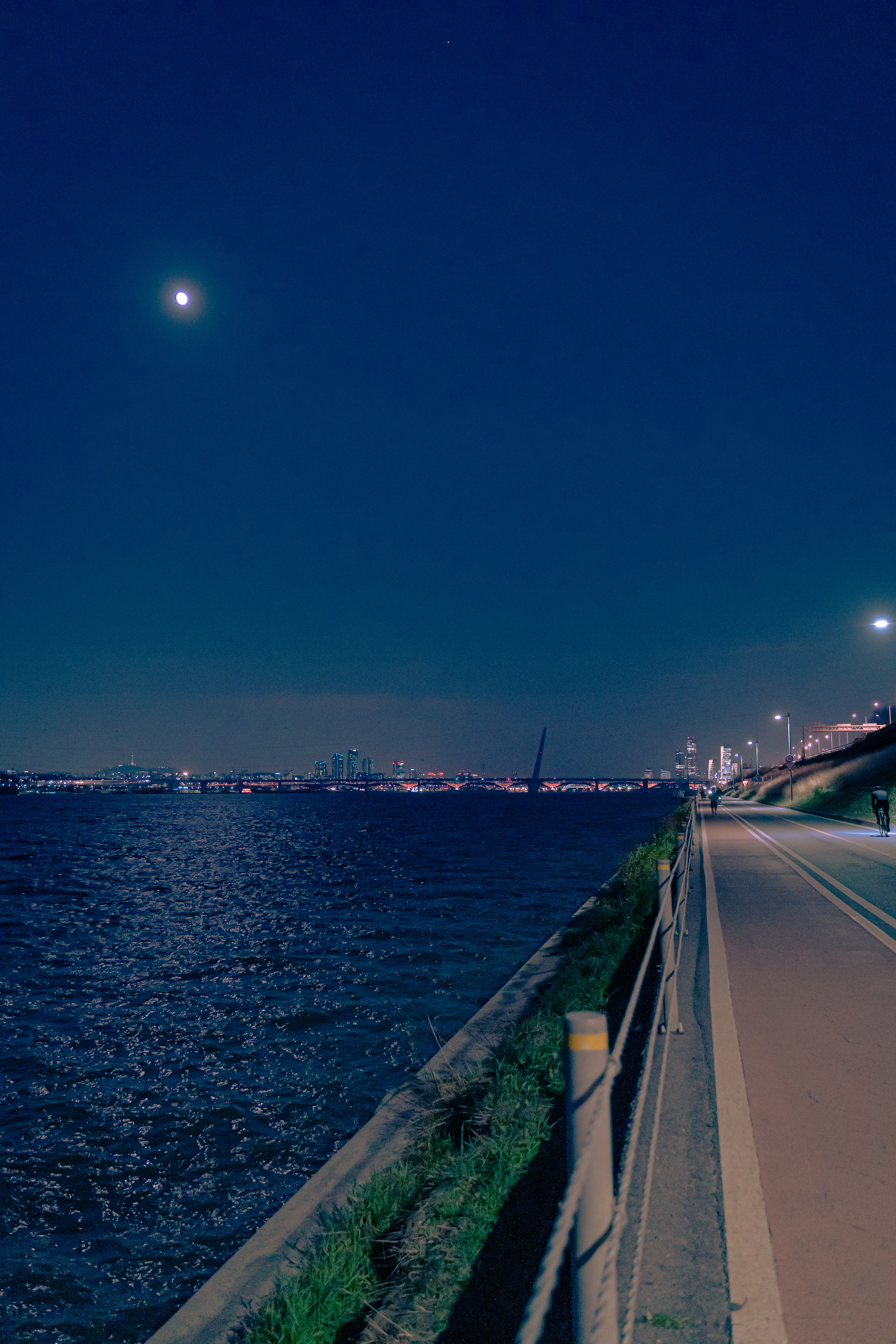 Moonlit River Walk with Distant City Glow